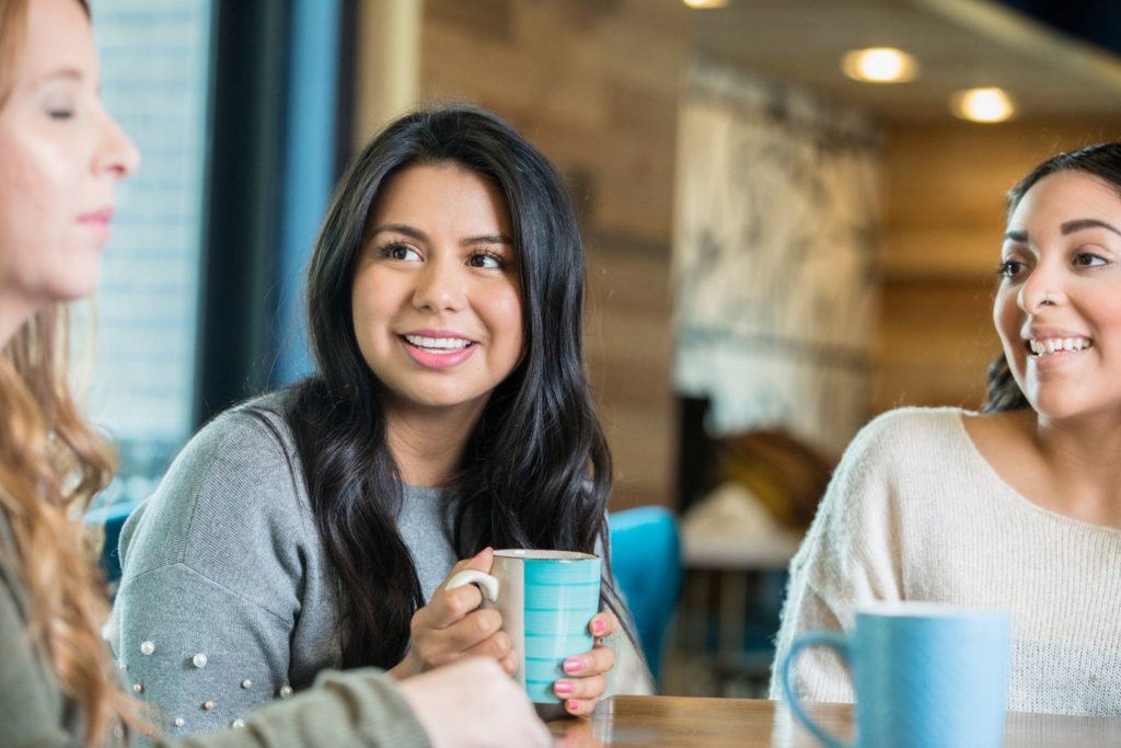 a group of women having a conversation over a cup of coffee