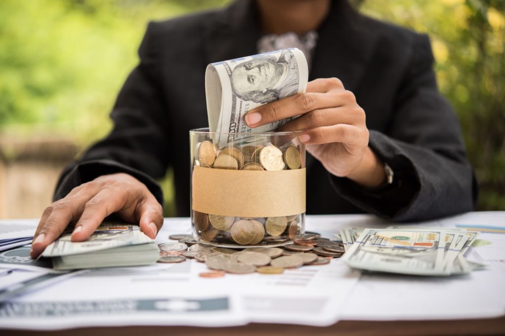 a person filling their savings jar