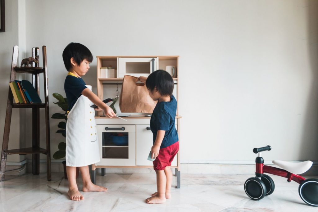 toddlers playing with a toy kitchen