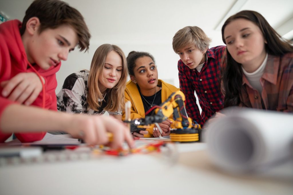 a group of tweens toying with various robotic parts