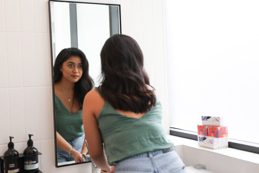 a woman looking in the mirror at herself confidently