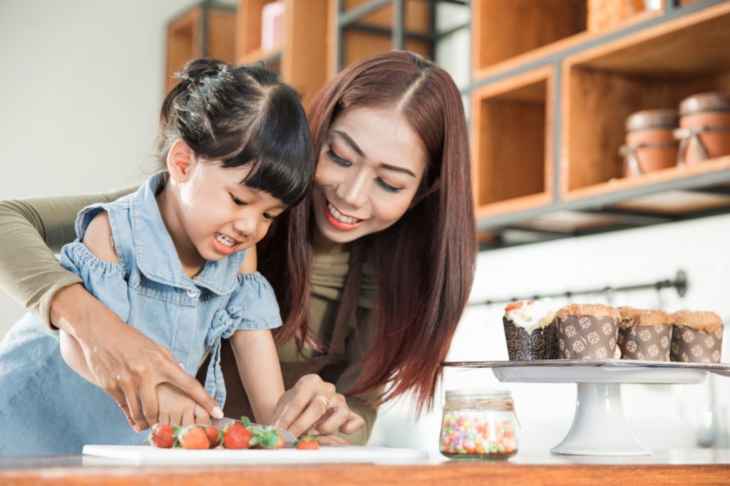 a mother and child making a snack in the kitchen