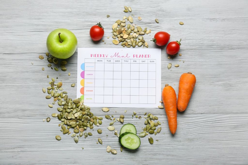 a meal plan schedule surrounded by foods full of protein 