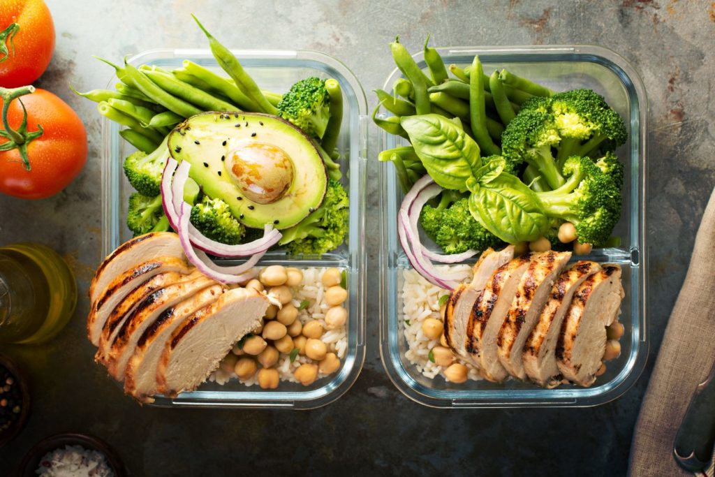 two meal prep containers filled with hearty meats and greens