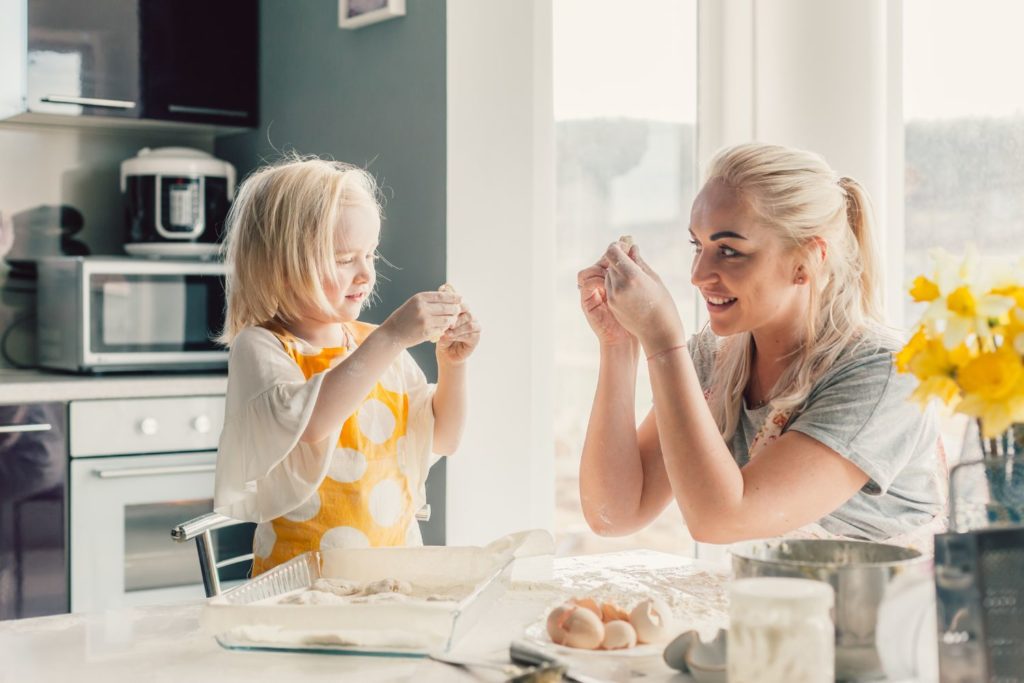 a child and mother baking in the kitchen together