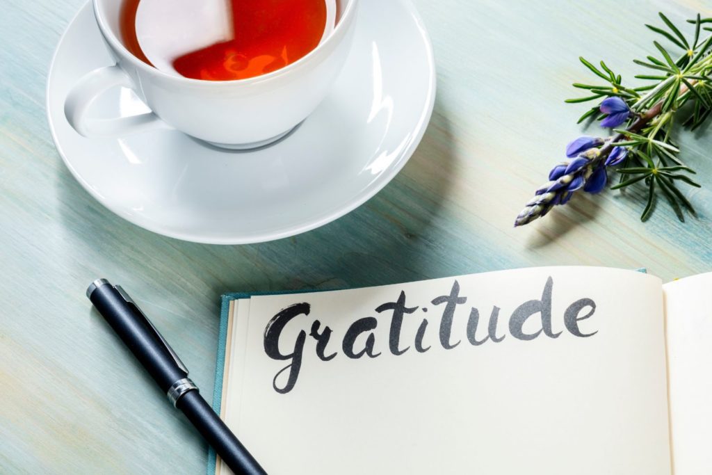 a gratitude journal and a cup of tea placed neatly on a coffee table waiting to be used